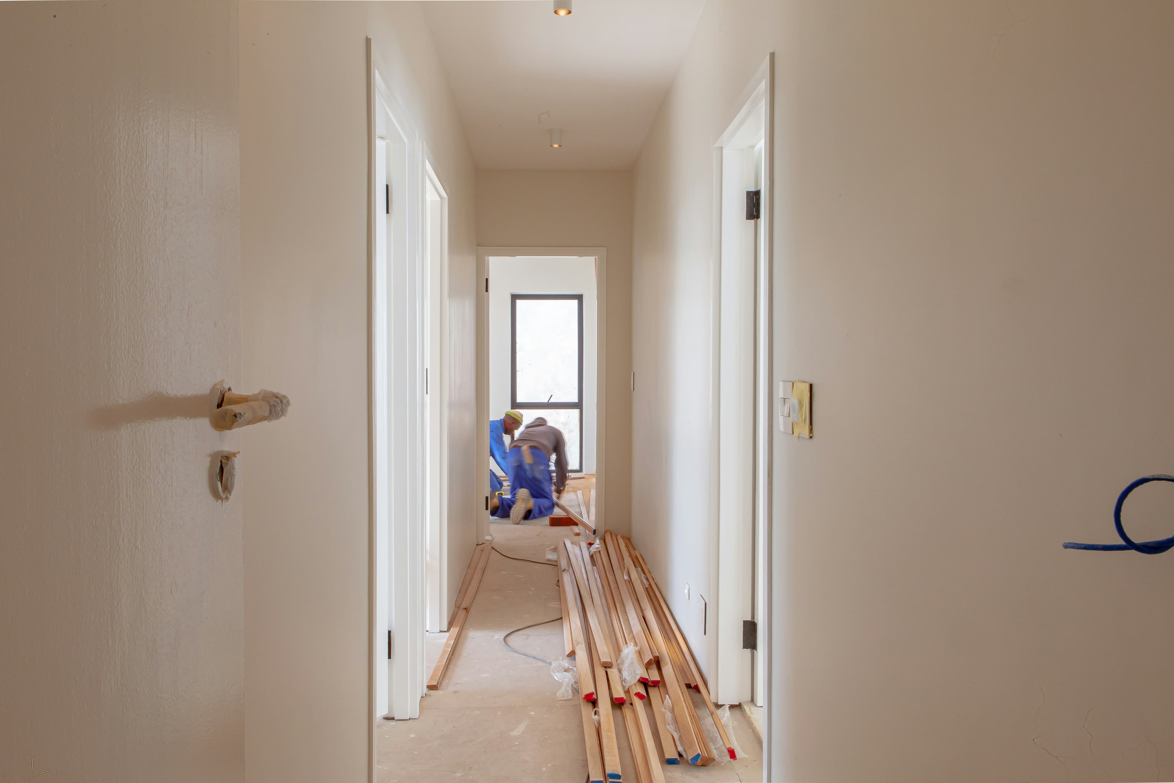 Tradespeople installing wooden flooring in a freshly painted home